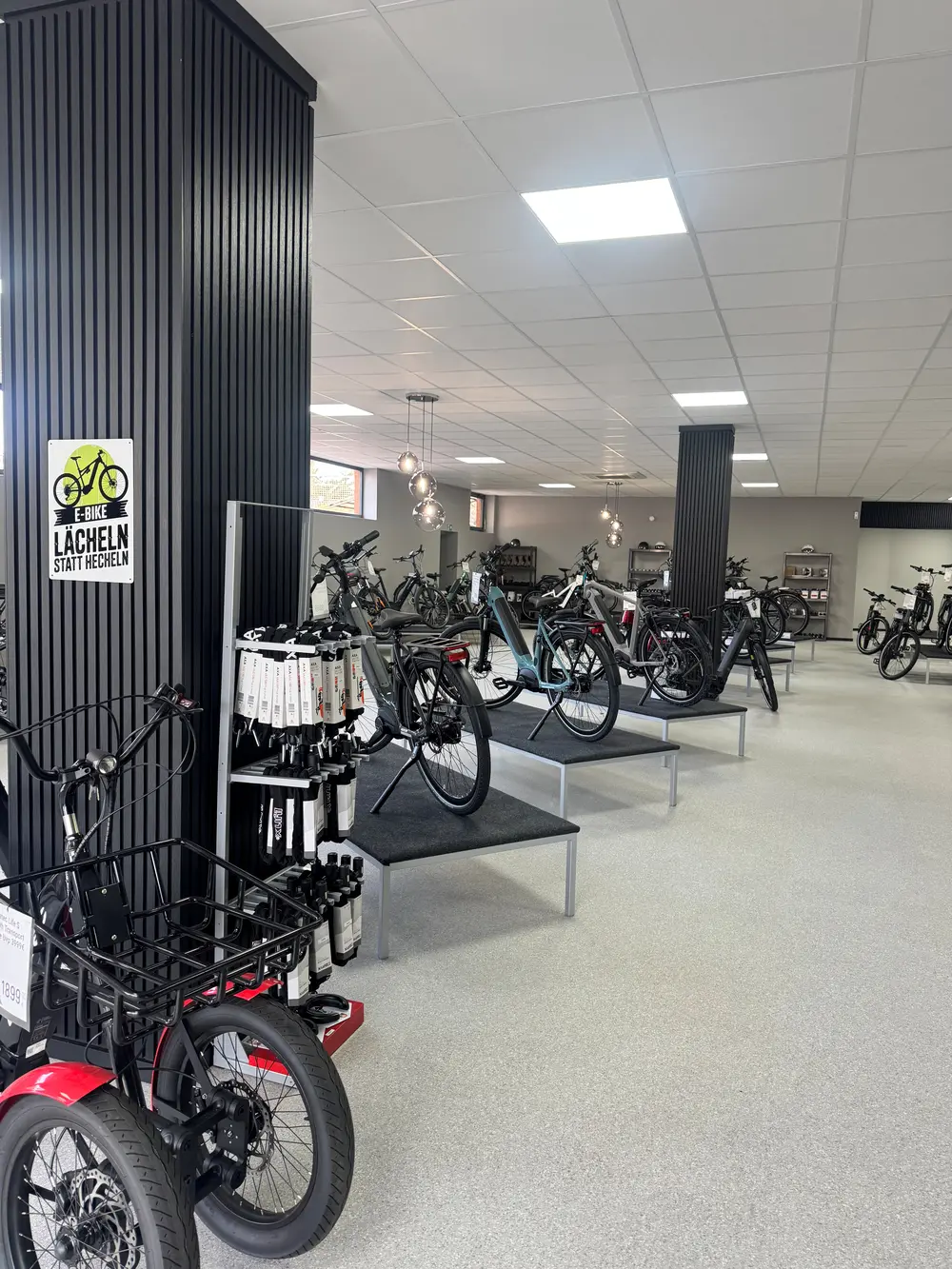 Ein heller Verkaufsraum mit modernen E Bikes auf Podesten und schwarzer Dekoration